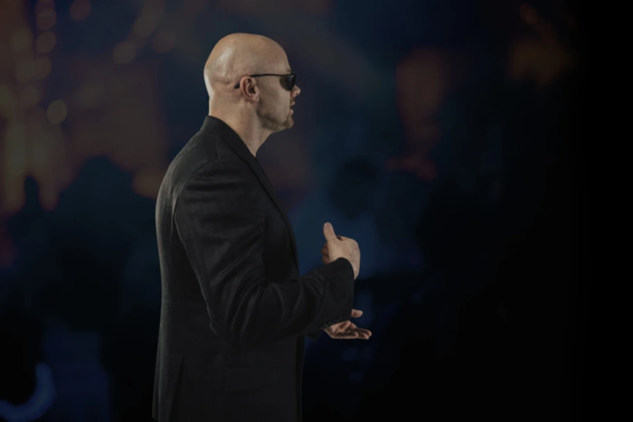 Side view of Chad speaking in front of a large audience